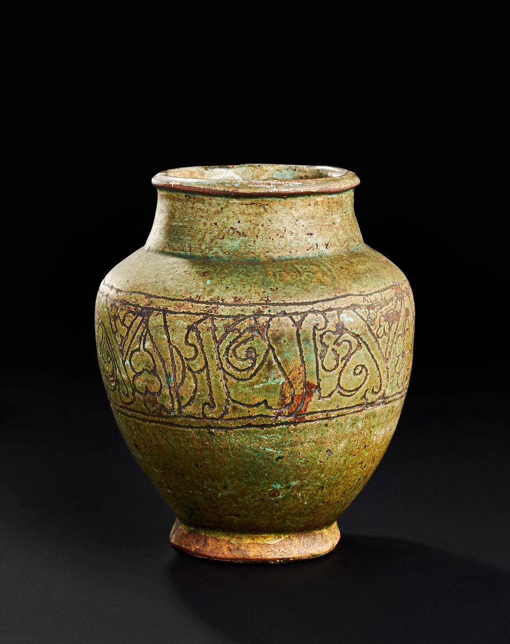 Lot 211: A RARE GREEN FATIMID GLAZED POTTERY VASE DEPICTING KUFIC INSCRIPTIONS, 10TH -12TH CENTURY