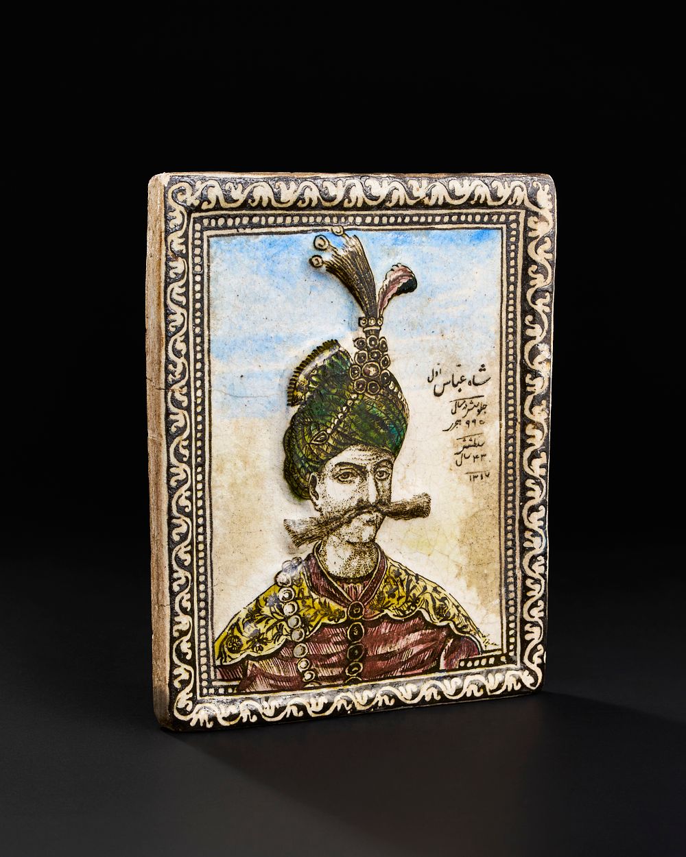 Lot 166: A QAJAR MOULDED POTTERY TILE DEPICTING SHAH ABBAS THE GREAT, PERSIA, DATED AH 1317/ AD 1899-1900