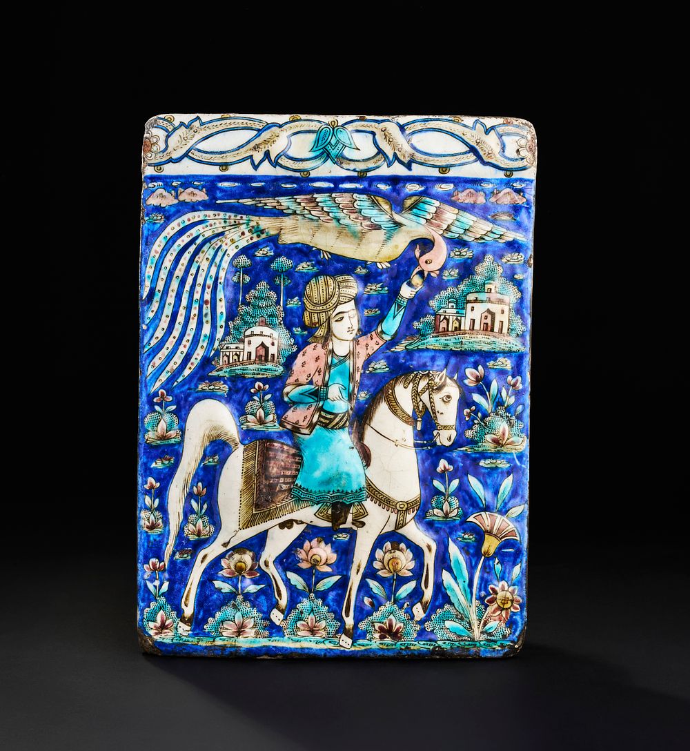 Lot 168: A LARGE QAJAR GLAZED MOULDED POTTERY TILE DEPICTING A MAN ON A HORSE, 19TH CENTURY