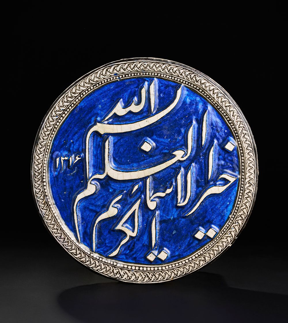 Lot 169: A LARGE ROUND QAJAR MOULDED POTTERY TILE DATED AH 1314/A.D. 1896
