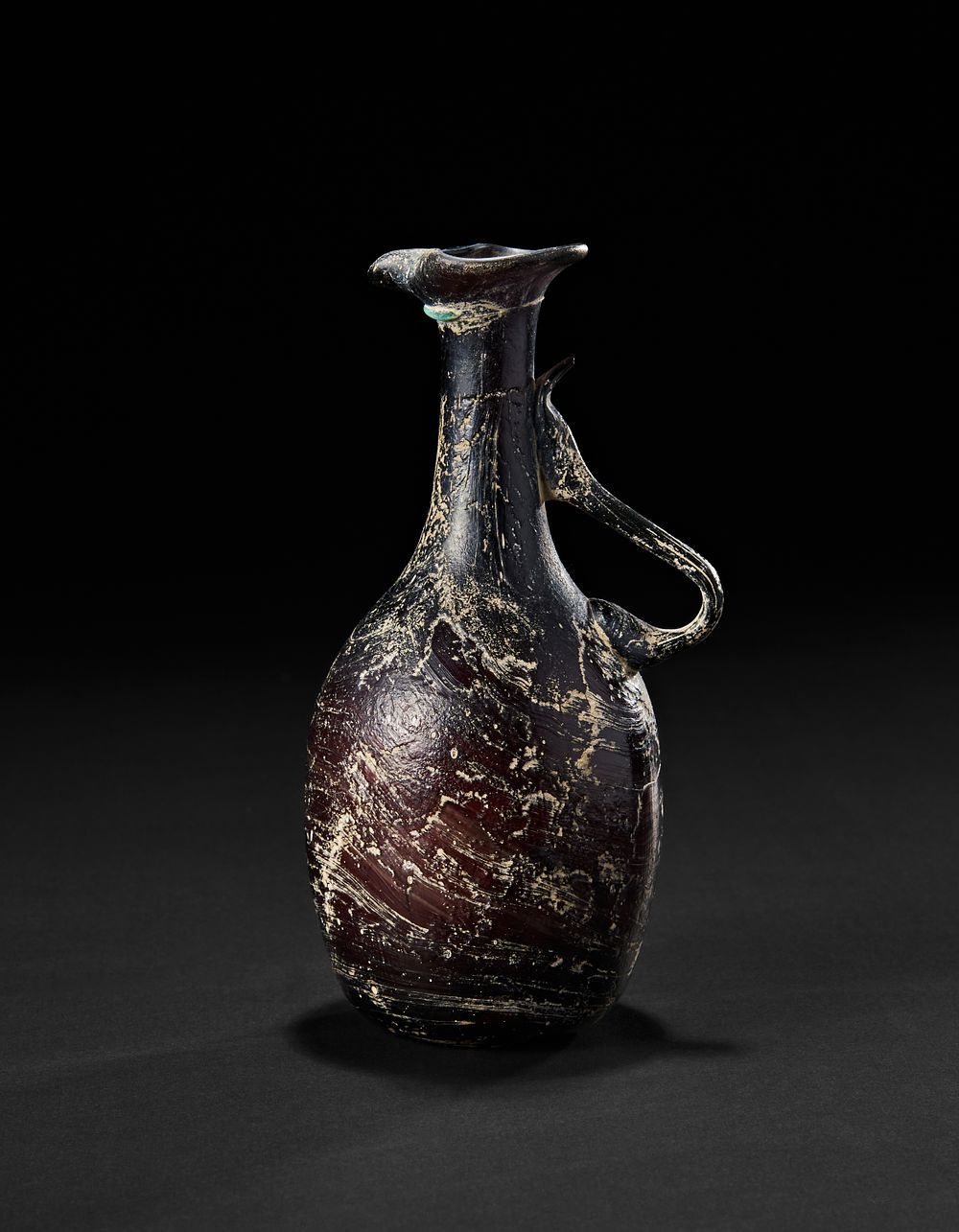 Lot 198: AN EARLY ISLAMIC UMAYYAD BROWN GLASS JUG, POSSIBLY 7TH - 8TH CENTURY