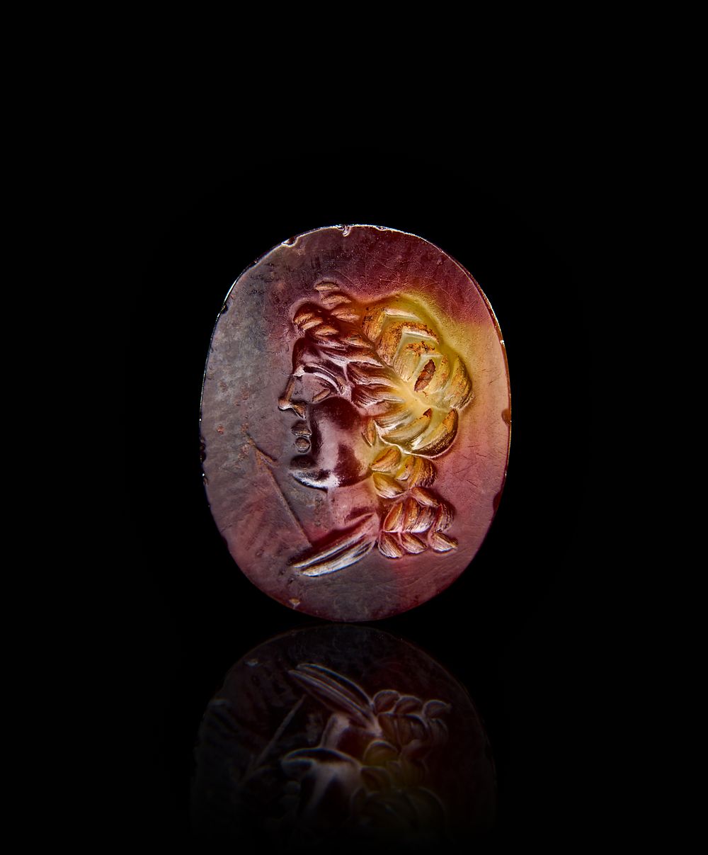 Lot 215: A ROMAN AGATE INTAGLIO DEPICTS HEAD OF A DEITY AND ARROW, 1ST - 2ND CENTURY A.D