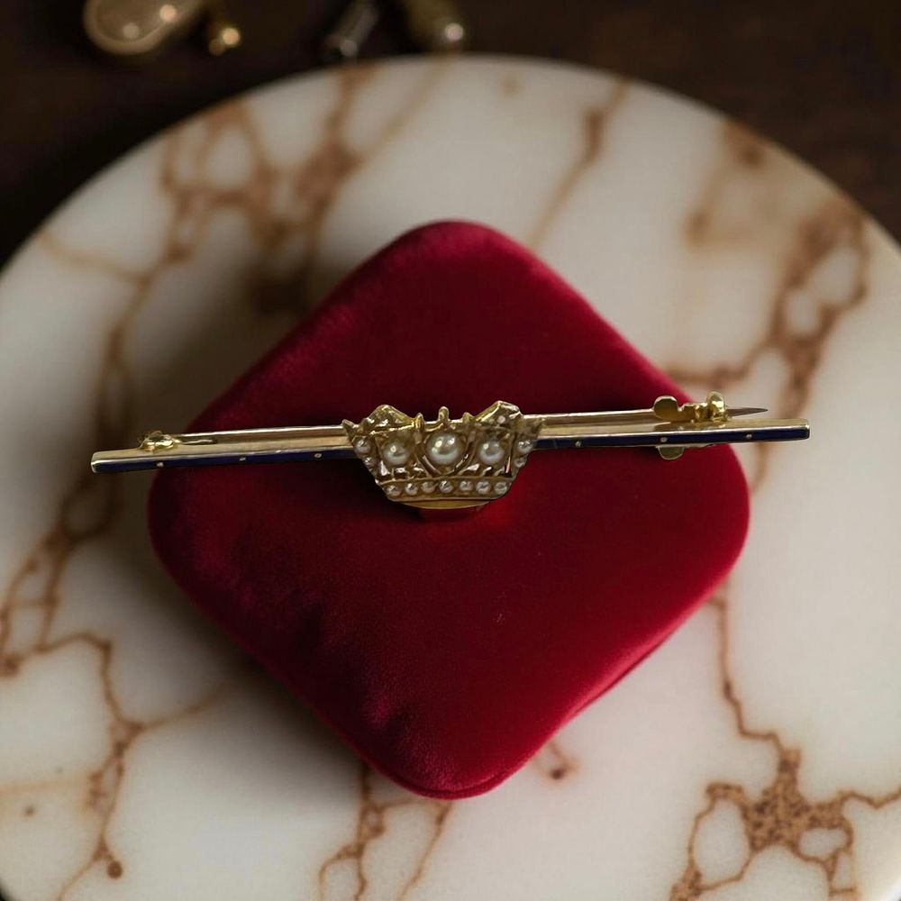 Lot 337: 14ct Gold brooch with a crown, blue enamel and seed pearls.