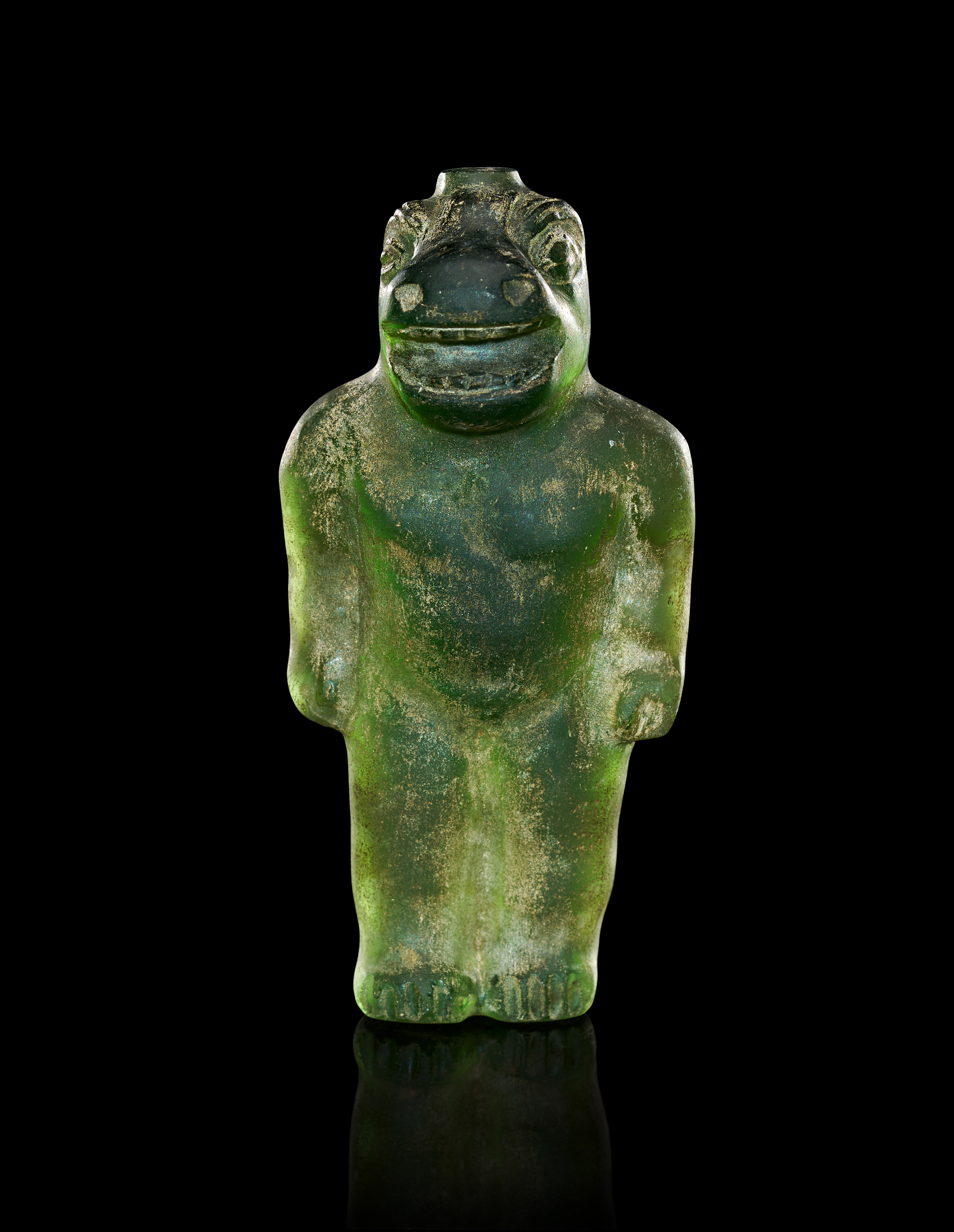 A TRANSLUCENT GREEN GLASS ZOOMORPHIC FIGURINE, PROBABLY PTOLEMAIC PERIOD OF EGYPT