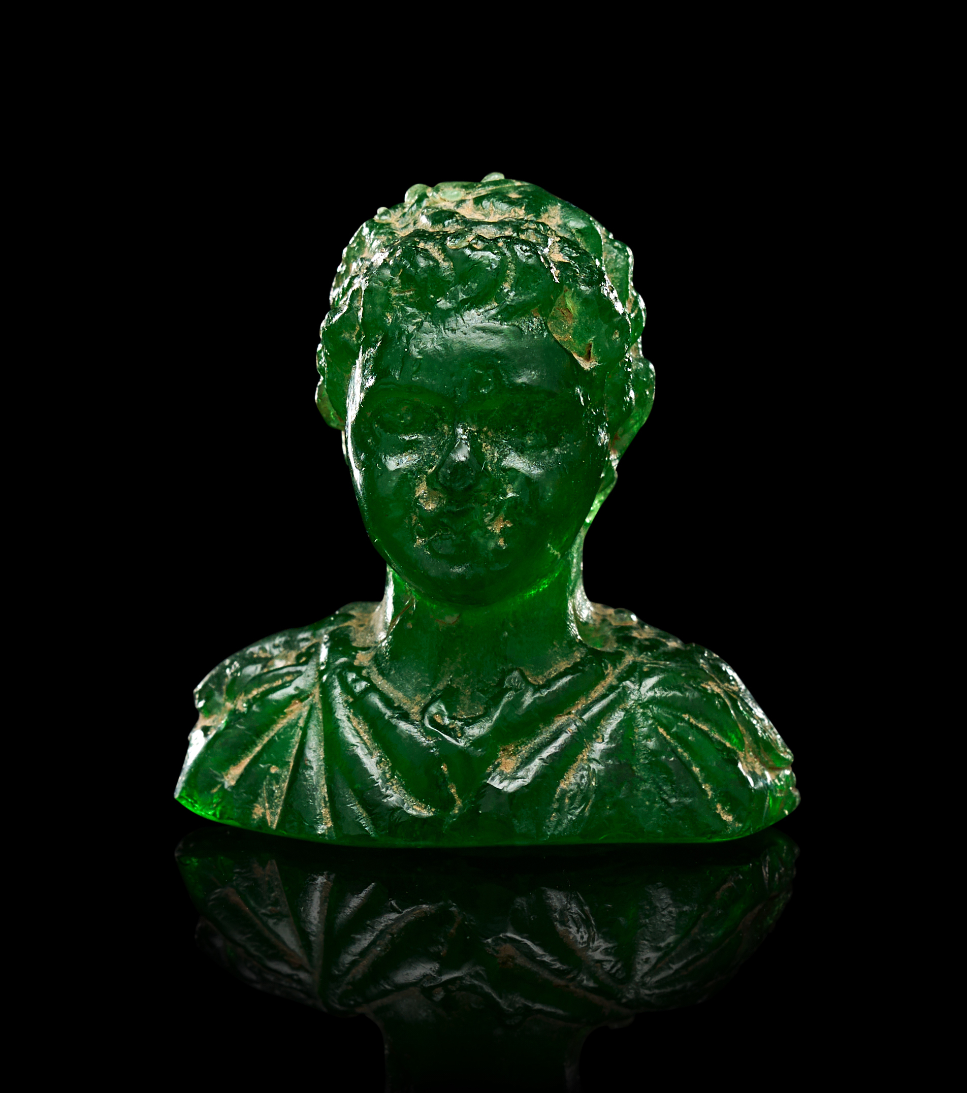 A GREEN GLASS ROMAN BUST OF A YOUTH RESEMBLING THE YOUNG EMPEROR
GETA, CIRCA 2ND CENTURY B. C.