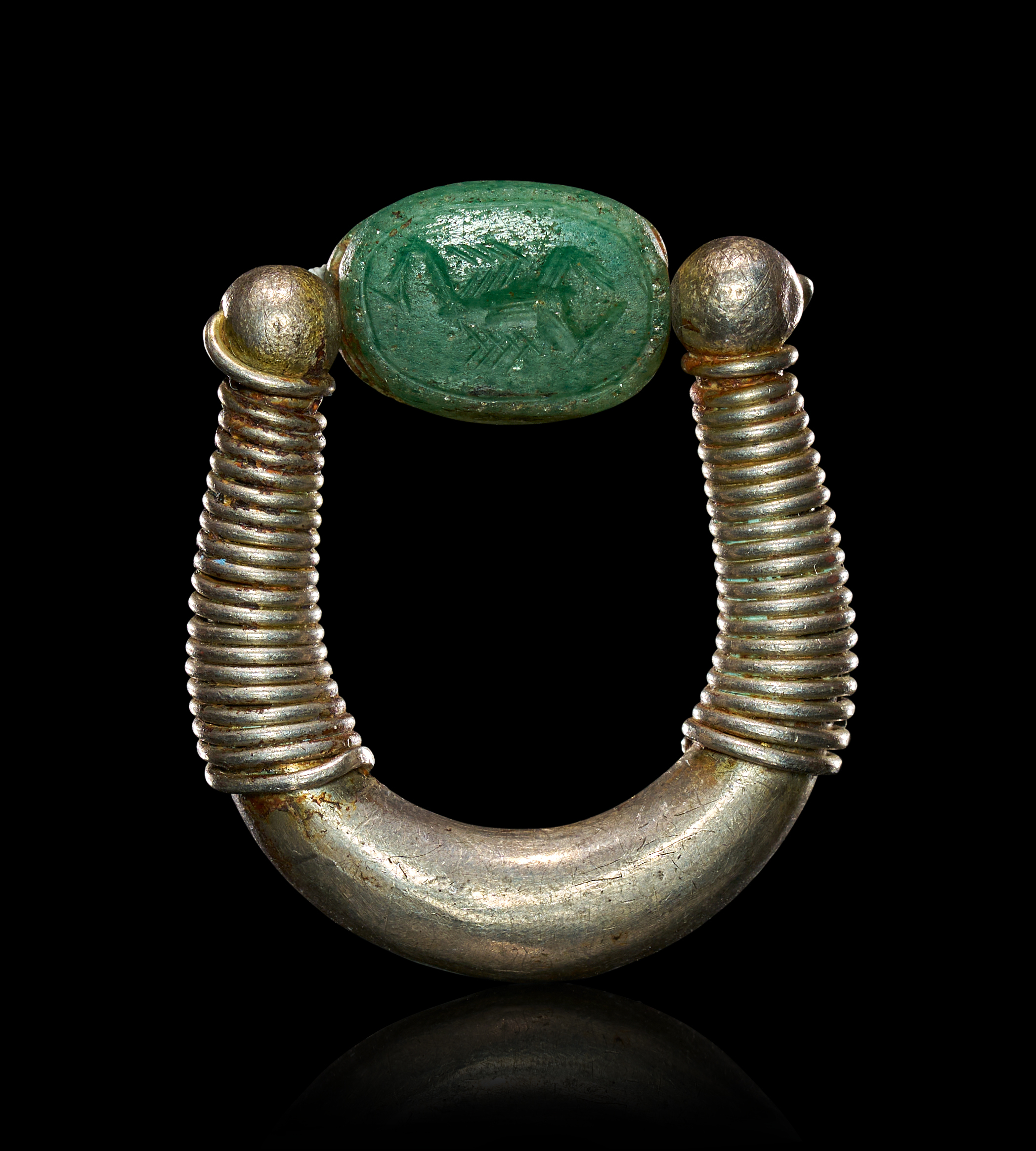 AN EGYPTIAN SILVER-COLOURED METAL SWIVEL RING WITH CARVED GREEN SCARABOID BEAD, NEW KINGDOM PERIOD.