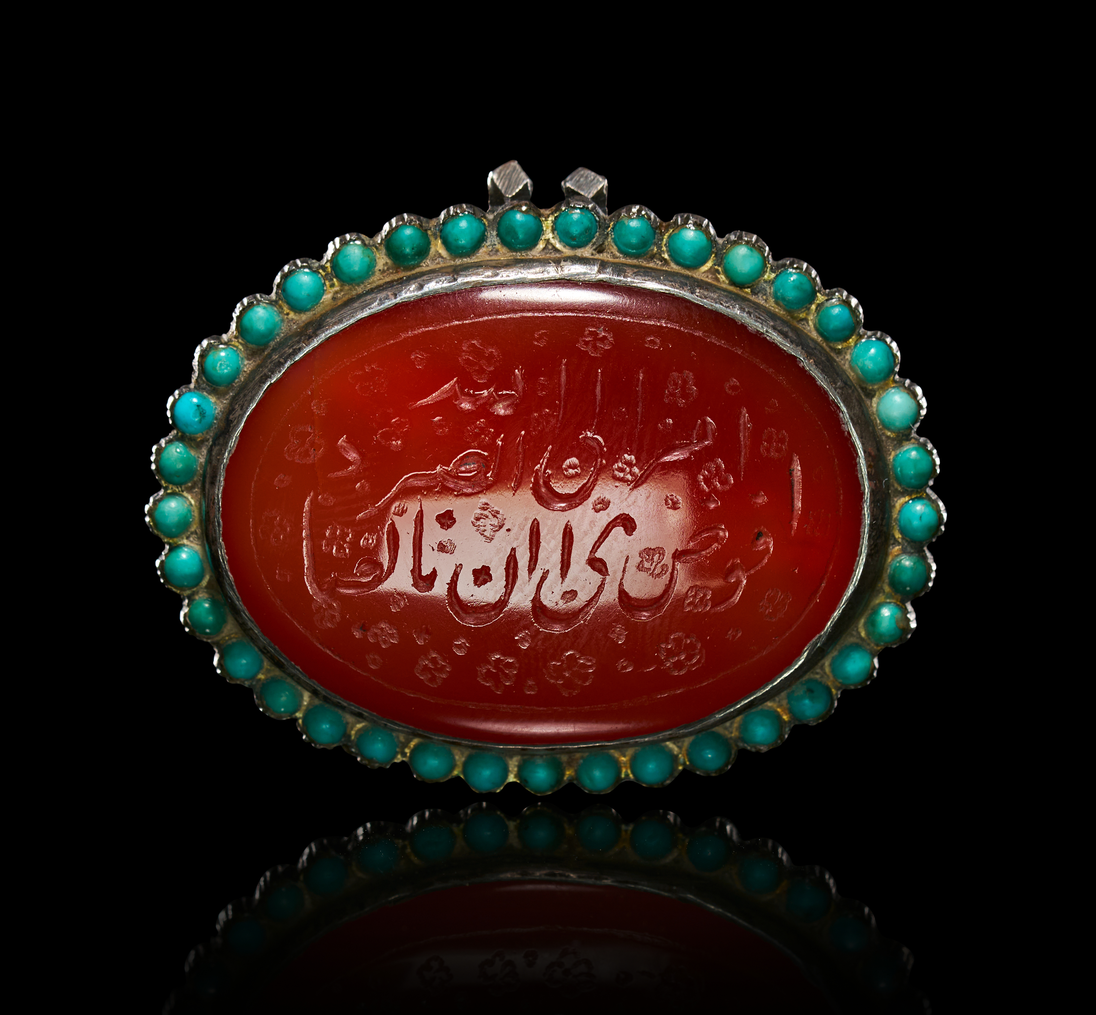 A HIGHLY DECORATED SILVER TALISMANIC PENDANT SET WITH A CALLIGRAPHIC CARNELIAN AND TURQUOISE, QAJAR, 19TH CENTURY
