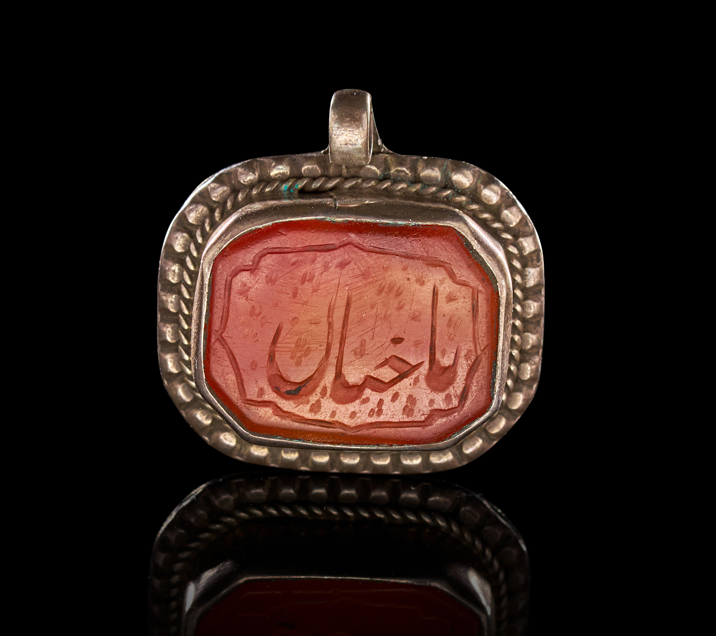 AN ISLAMIC SILVER MOUNTED CARNELIAN AMULET PENDANT, PERSIA, 19TH CENTURY