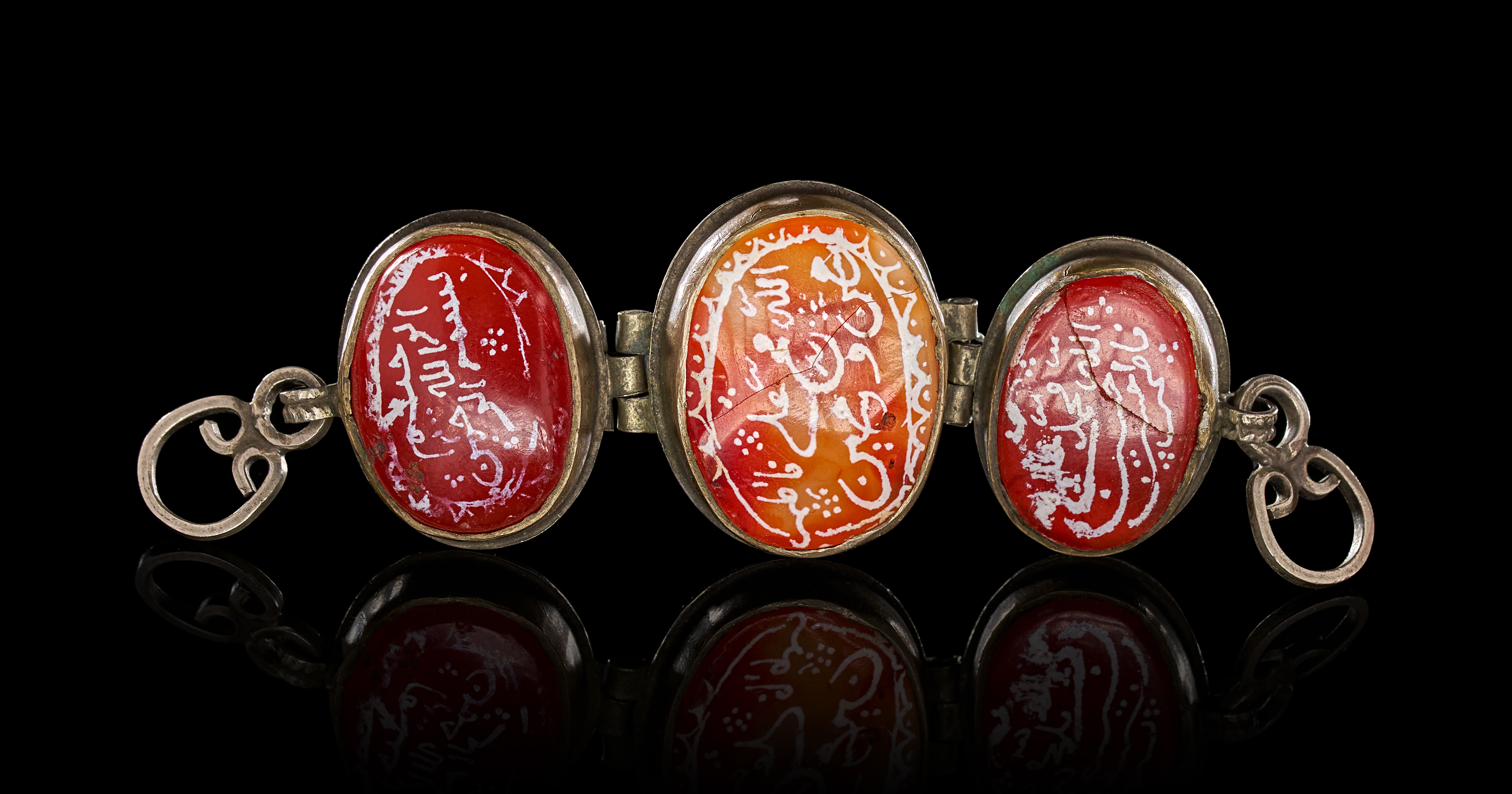 A SILVER-TONED AND INSCRIBED CARNELIAN THREE-PANEL BAZUBAND, 19TH CENTURY