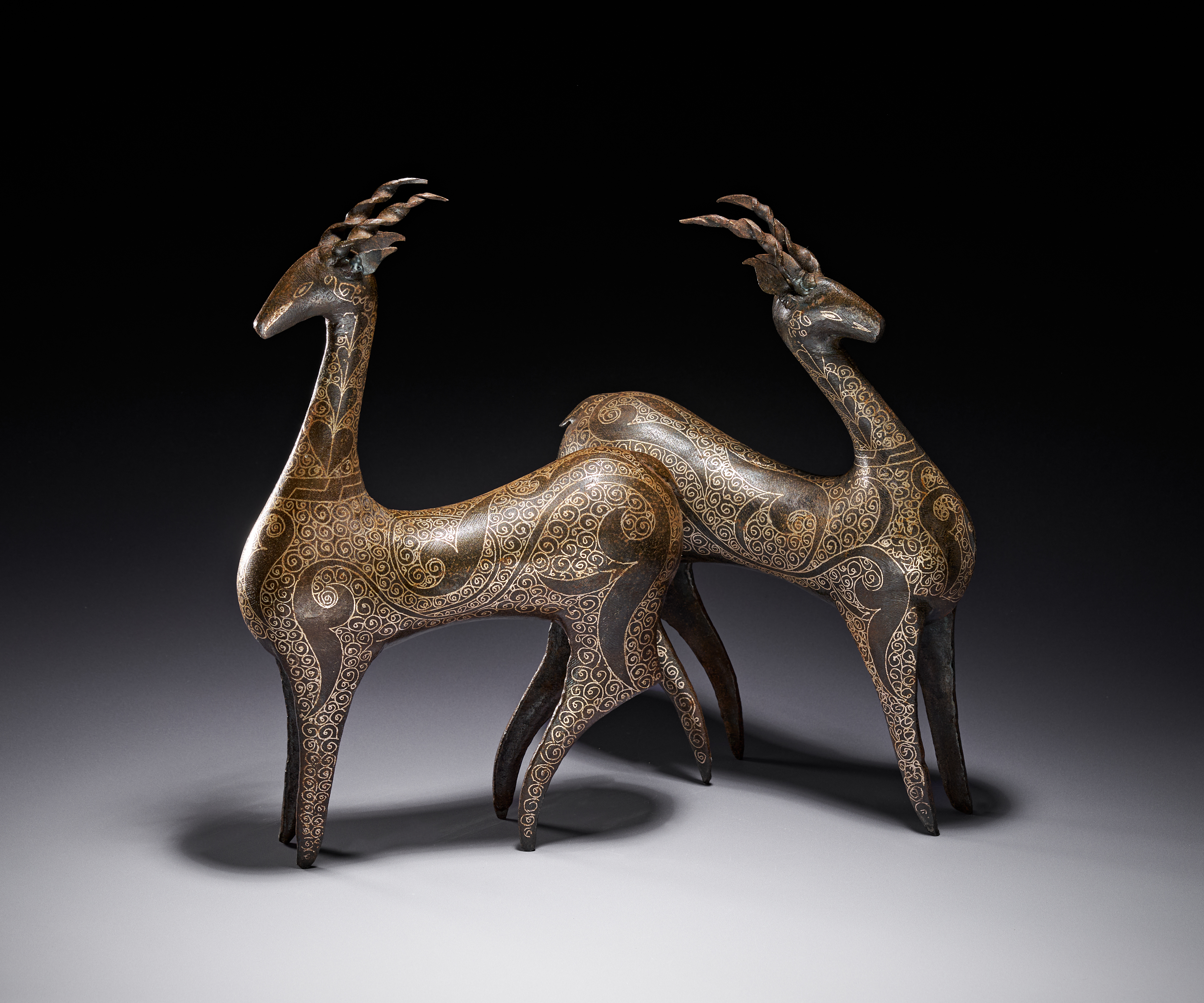 A PAIR OF PERSIAN QAJAR STYLE DAMASCENED STEEL FIGURES OF DEER, 20TH CENTURY