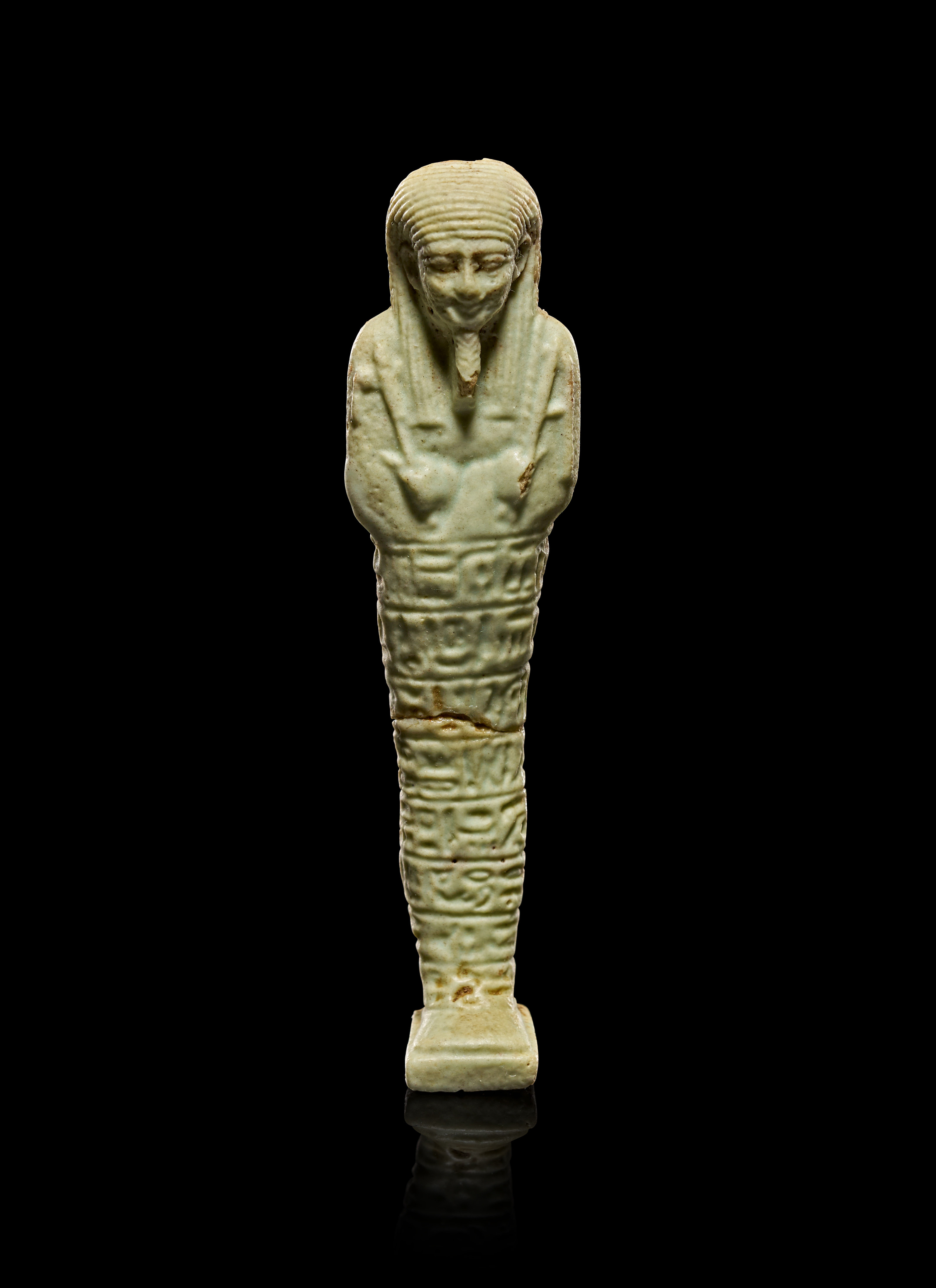 AN EGYPTIAN PALE GREEN GLAZED FAIENCE USHABTI, LATE PERIOD, CIRCA 664–332 BC