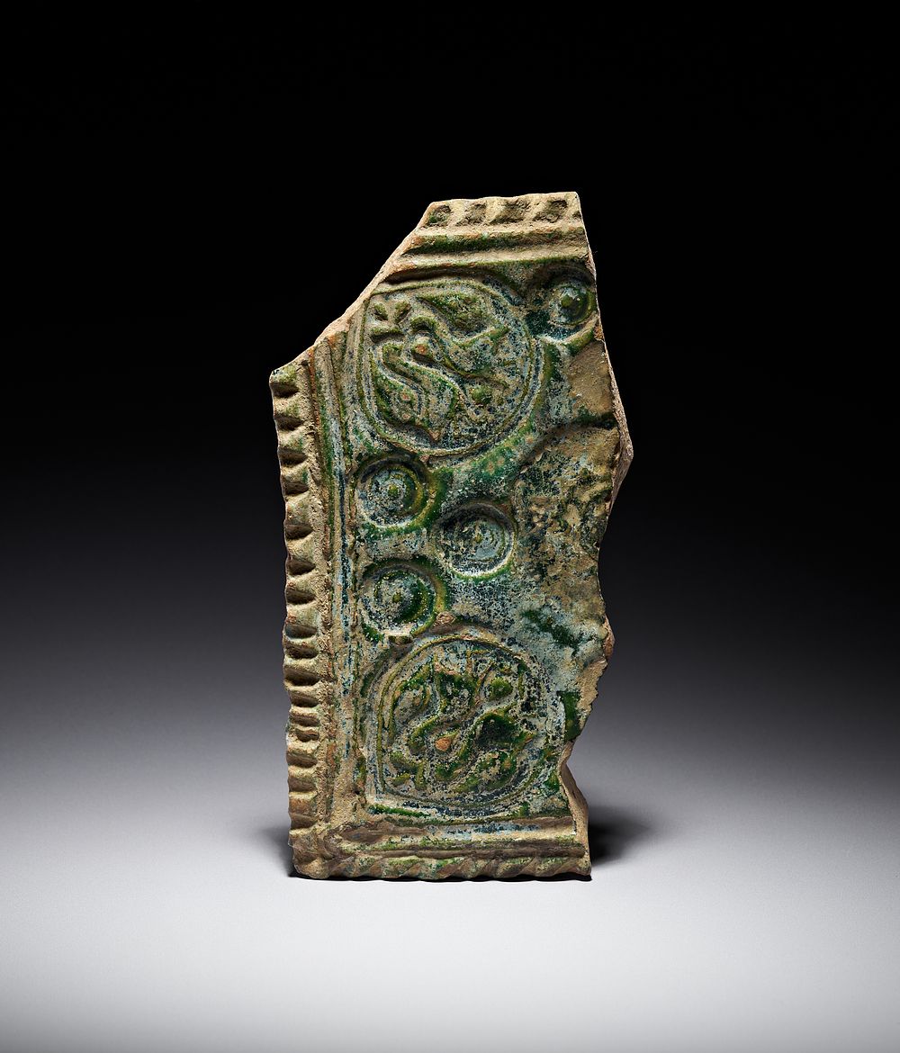 Lot 197: A RARE UMAYYAD MOULDED GREEN-GLAZED CERAMIC TILE FRAGMENT, EASTERN MEDITERRANEAN, 8TH CENTURY