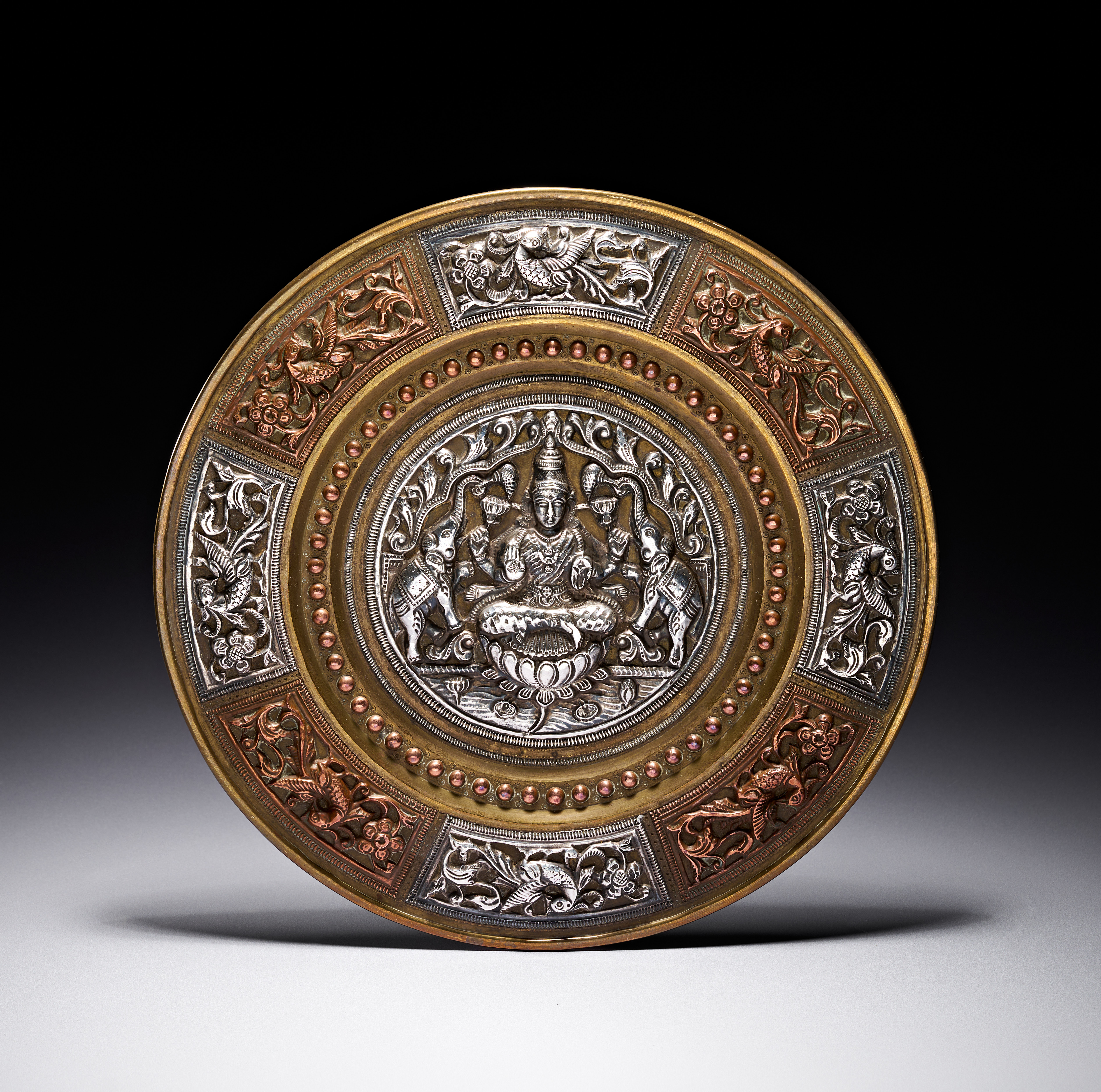 A SOUTH INDIAN THANJAVUR SILVER AND COPPER ENCRUSTED BRASS PLATE, LATE 19TH CENTURY