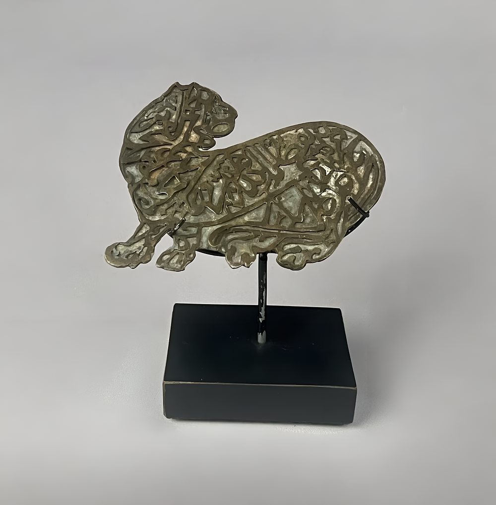 Lot 237: A PERSIAN OR INDO-PERSIAN SILVERED COPPER-ALLOY ZOOMORPHIC CALLIGRAPHIC PLAQUE OF A LION