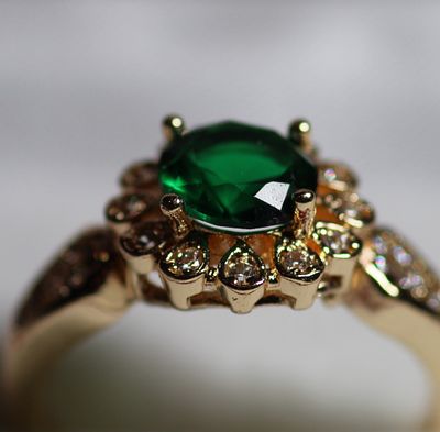 טבעת מיוחדת במינה מזהב גולדפילד צהוב בשיבוץ אבן ספיר ירוקה במרכז ואבני זירקוניה סביב בעבודה 