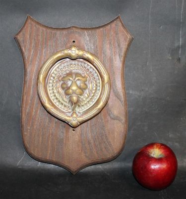 Bronze lion head door knocker mounted on oak shield form plaque. 11 3/4"h x 8 1/2"w Door 