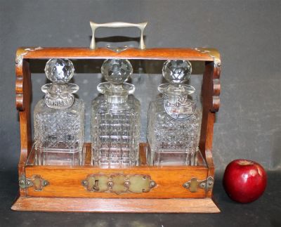 English 3 bottle tantalus set in oak and silverplate carrier. Early 20th century. 13"h x 14 