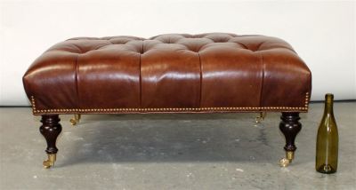 Tufted leather ottoman on turned legs with casters. 21st century. 17 1/2"h x 41 1/2"l x 32"w