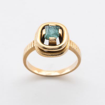 Sortija de estilo geom&eacute;trico en oro con esmeralda talla octogonal engastada en garras y brazos 