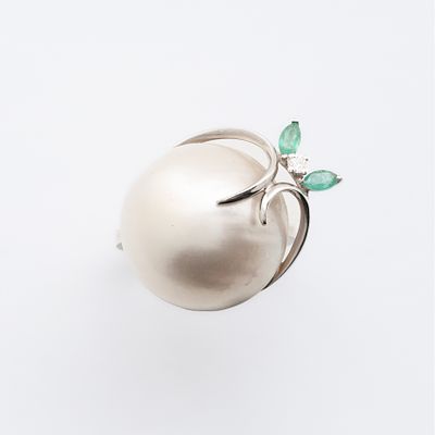 Sortija en oro blanco con perla japonesa de 19 mm. abrazada por roleos de diamantes talla 