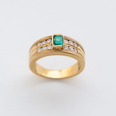 Sortija en oro con esmeralda central talla octogonal custodiada por bandas de diamantes talla 