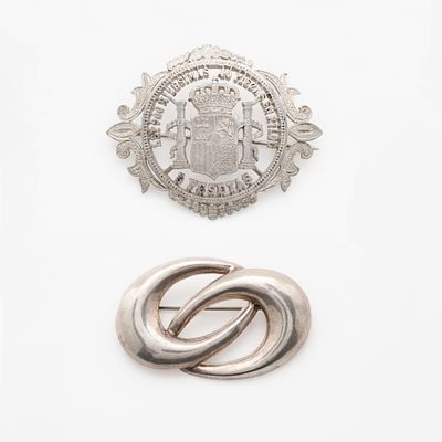 Dos broches calados en plata. Uno simulando una moneda de 2 pesetas, 5,6 x 4,5 cm. y el segundo 