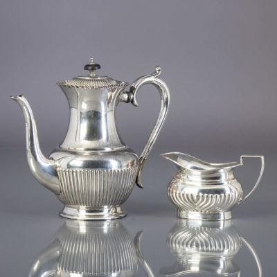 CAFETEIRA E LEITEIRA. Em casquinha, decora&ccedil;&atilde;o gomada, leiteira marcada Mappin &amp; Webb. Sinais 