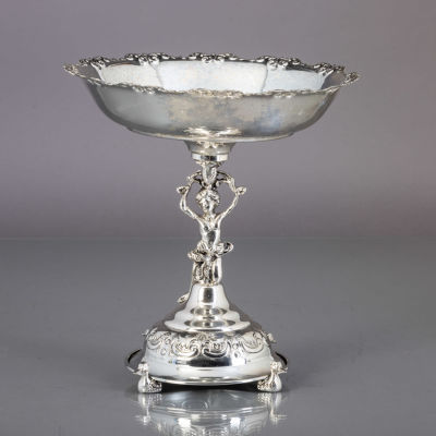 FRUTEIRO COM P&Eacute;. Em metal prateado, decora&ccedil;&atilde;o relevada, p&eacute;s na forma de patos, fuste 