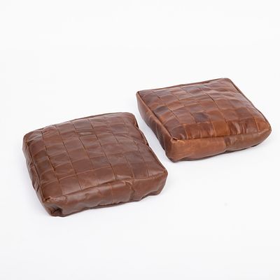 DUAS ALMOFADAS. Estofadas a pele castanha. Sinais de uso e pequeno defeitos.Dim.: 10x44x44 cm.