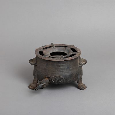 FOGAREIRO. Em ferro, decora&ccedil;&atilde;o relevada e p&eacute;s de garra, marcado E. Adnet Paris. Falhas, defeitos 