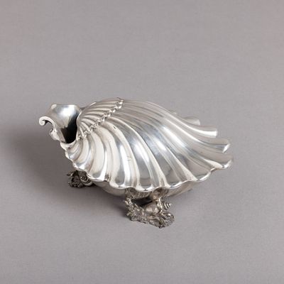 CONCHA. Em metal prateado, decora&ccedil;&atilde;o relevada "concheados e b&uacute;zios". Sinais de uso.Dim.: 9x21x13 