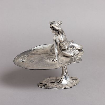 CENTRO DE MESA ARTE NOVA. Em liga de metal prateado, decora&ccedil;&atilde;o relevada "figura feminina 