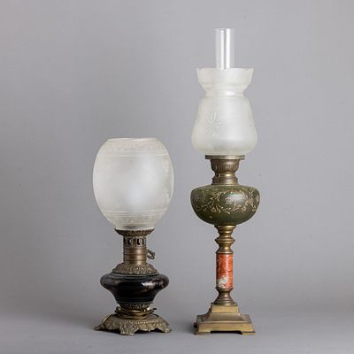 DOIS CANDEEIROS DE MESA. Em metal relevado e outros materiais, um a petr&oacute;leo, dep&oacute;sitos em vidro 