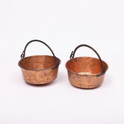 DOIS TACHOS. Em cobre, pegas em ferro. Amolgadelas, pequenas falhas e leve oxida&ccedil;&atilde;o.Dim.: 24x43 