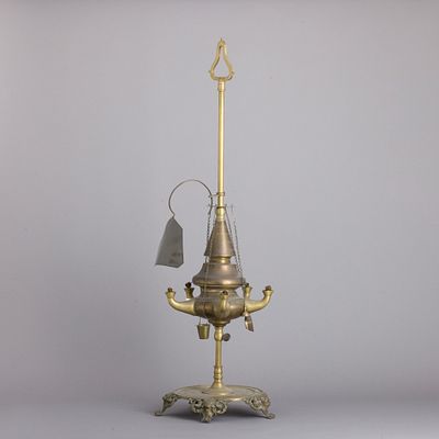 GRANDE CANDEIA DE AZEITE. Em metal amarelo, com quebra-luz e diversos utens&iacute;lios, base circular 