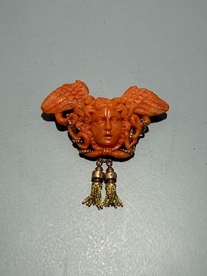 Pregadeira de coral e ouro com figura de medusa. 
Sem marcas de garantia. 
Sinais de 