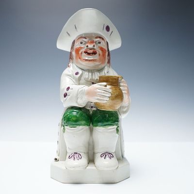 English Pearlware Toby Jug, hand-painted in a palette of green, white, brown, and purple. The 