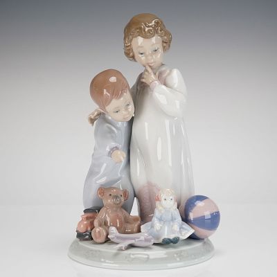 Lladro Glazed Porcelain Figurine of Children Sharing a Secret. A glazed porcelain figural group 