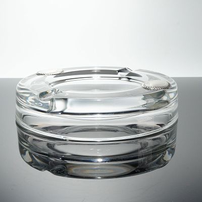 Glass Ashtray with Silver Toned Medallions. A circular ashtray crafted from heavy clear glass. 
