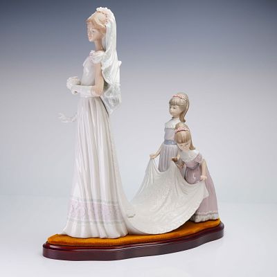 Lladro Here Comes the Bride Porcelain Sculpture. The sculpture features a bride in a white gown 