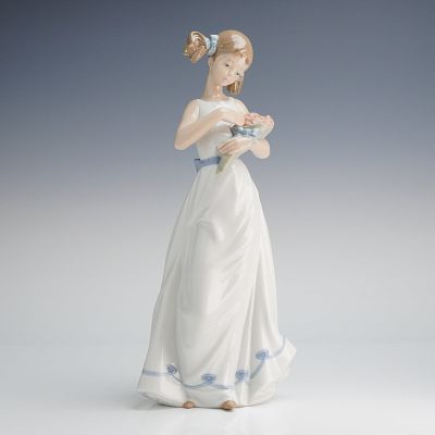 NAO by Lladro Porcelain Figurine, Girl with Holding a Bouquet. A NAO by Lladro glazed porcelain 