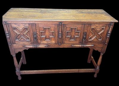 JACOBEAN REVIVAL OAK SIDEBOARD . WITH A RECTANGULAR MOLDED-EDGE TOP ABOVE FOUR PANELED COVERED 