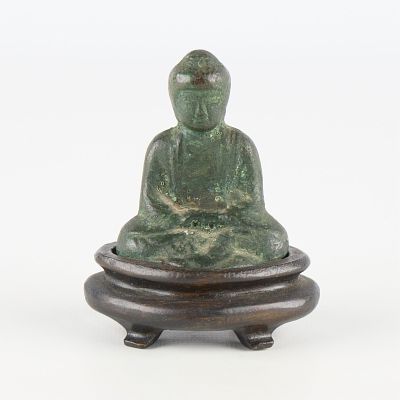 Seated Bronze Buddha Sculpture. Seated smiling bronze Buddha figurine set on a carved wooden
