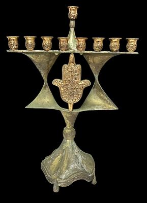 חנוכייה גדולה ממתכת מצופה כסף עם פטינה, מעוטרת בחמסה מרכזית וחריטות של ירושלים על הקנים. עיצוב