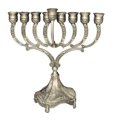 חנוכייה בעלת שמונה קנים ושמש מרכזי, ממתכת בציפוי כסף, עם עיטורים פרחוניים ומוטיבים מגולפים. 