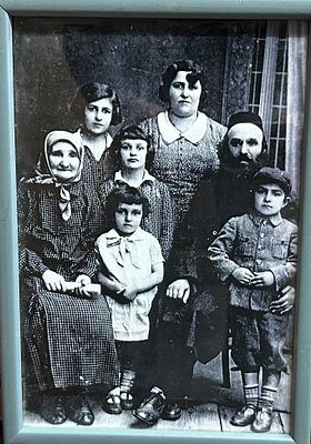צילום ישן בשחור־לבן המציג משפחה יהודית מסורתית, הכוללת מבוגרים וילדים בלבוש תקופתי.
צילום מבוים 