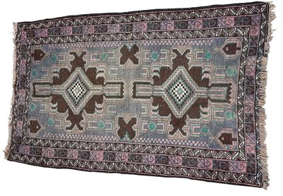 שטיח דקורטיבי בעבודת יד עם דוגמאות גיאומטריות ואתניות בגוונים עדינים של אפור, חום וטורקיז. 