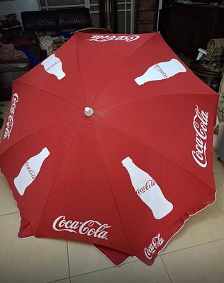 שמשיית פרסום גדולה של Coca-Cola בצבע אדום עם לוגו ובקבוקי קוקה-קולה בלבן. מבנה חזק ובד עמיד. 