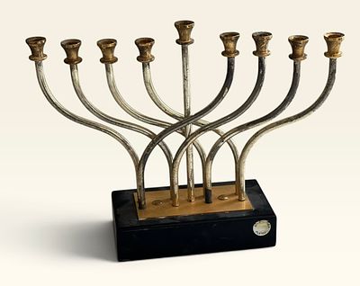 חנוכייה ממתכת מוזהבת, קנים שזורים, בסיס שחור
חנוכייה בעלת תשעה קנים (שמונה + שמש מרכזי גבוה). 