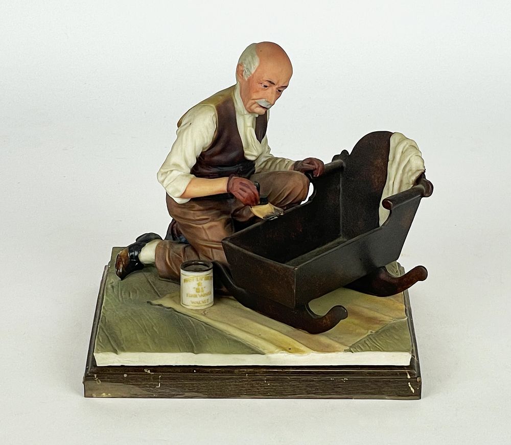 Polychrome artistic porcelain, marked Capodimonte, depicting a carpenter busy ﬁnishing a baby's 